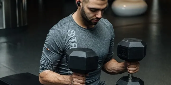 A man doing dumbbell bench press in the gym.