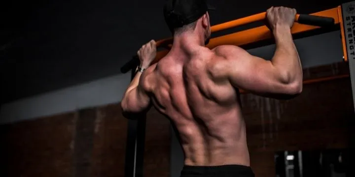 A man doing wide grip pull ups.