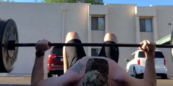 The start position for a barbell floor press, before initiating the concentric portion.