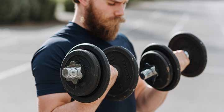 A lifter performing curls with adjustable dumbbells.