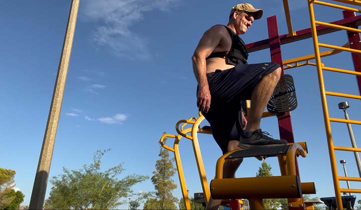 The author of Lunch Break Fitness performing a weighted step up on a bench at the park.