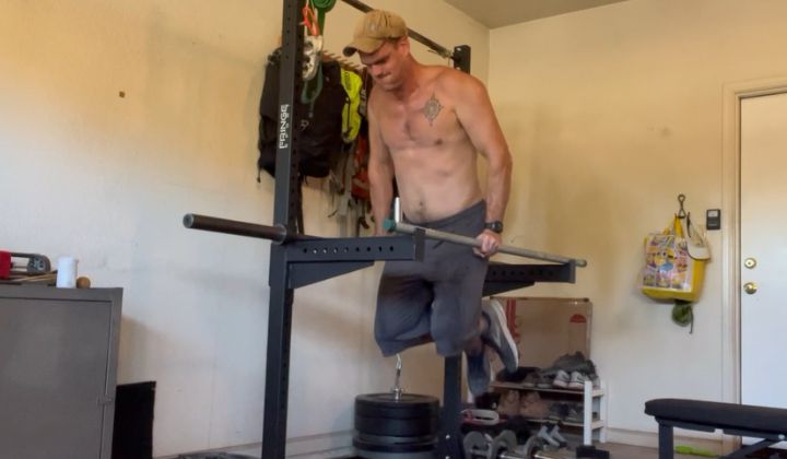 The author of Lunch Break Fitness in the top position of a parallel bar dip in his garage.