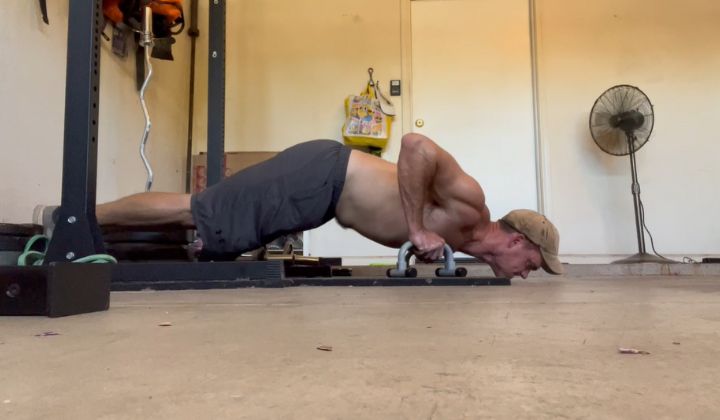 The author of Lunch Break Fitness performing an "upper chest" push-up on low parallettes.